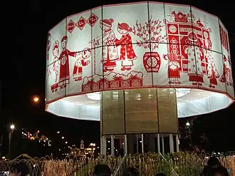 A large round white fabric band decorated with red figures and images for Tết