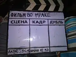 A clapperboard with a dry-erase display being used for a Russian-language film.