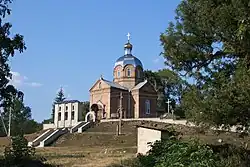 A church atop a small hill with trees visible at each side of the photograph.
