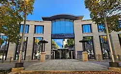 The entrace to a modern, three-floor office building. It features a symmetrical facade with beige stone walls and large windows. In the middle of the central glass front is a sign reading "Rockstar North".