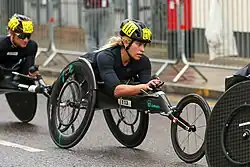 White woman dressed in black in a black wheelchair
