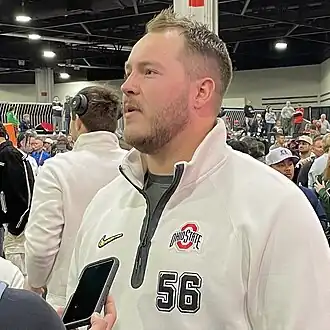 Football player standing and answering questions.