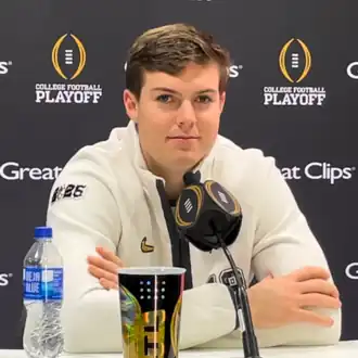 A football player sitting in front of a microphone.