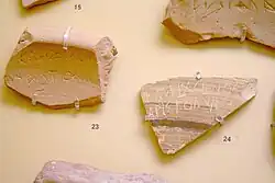 An image of an ostrakon, a piece of pottery used for voting in ancient Athens, inscribed with the name of Callixenus, who was proposed for ostracism. The artifact is displayed in the Ancient Agora Museum in Athens