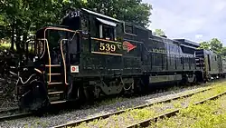 A GE B32-8 in the Western Maryland "Fireball" livery and the number 539 sits idle on the woods-lined tracks leading into Frostburg, MD.