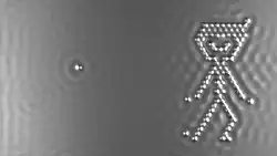 An image of a small boy on the right made out of silvery dots against a gray background, with a single dot on the left