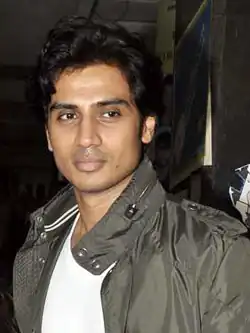 Shiv Panditt in a white T-shirt and camo jacket, looking away from the camera