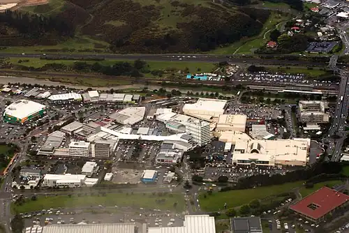 Viewed from west in 2013. In upper right with the crowded parking lot is Porirua Station. North City Shopping Centre is on right (tan coloured building with Kmart and Farmer's logo). State Highway 1 (SH 1N) and railway are at top. Green-walled building on left is a Countdown supermarket.