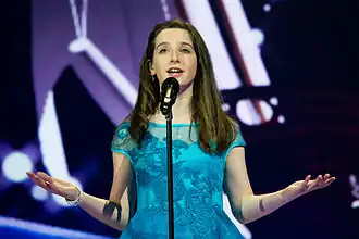 a teenage girl singing on stage