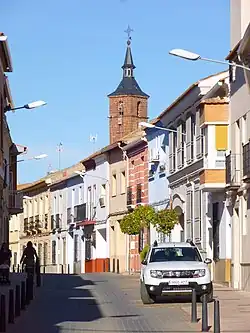 Street with close two-stroy buildings in Alcázar de San Juan with a church in the background
