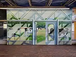 A mural of a fake doorway with cows grazing in a field