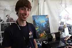 Beachum standing in front of a poster for Outer Wilds