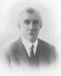 A middle-aged man with a moustache, in the formal dress of the early 20th century