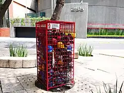 A metal cage encloses pieces of coal that bury helmets of various colors.