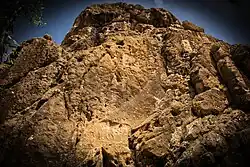 The relief is located on the top of a cliff towering over the village of Sarpol-e Zahab. A second relief (Parthian Empire period) appears below.