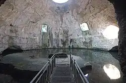 Bare concrete dome interior today called the Temple of Mercury with two square windows halfway up the dome on the far side, a circular oculus at the top, and a water level that reaches up to the base of the dome