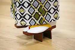 A close-up of a person wearing patterned kimono, white tabi, and tall geta.