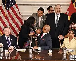 Wes Moore shakes Ivan Bates's hand after signing his bill to strengthen sentences for illegally carrying handguns
