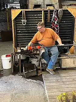man forming hot glass attached to pipe