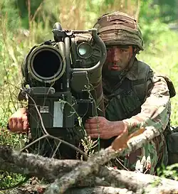 Colour photograph of a marine with an anti-tank weapon pointed at the camera.