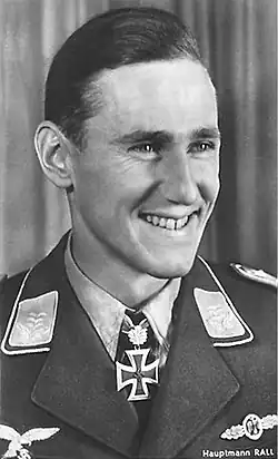 A black and white photograph, from the chest up, of a smiling young man wearing a uniform