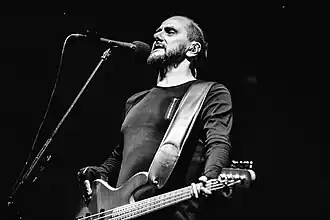 black-and-white image of Mariusz Duda playing bass guitar onstage