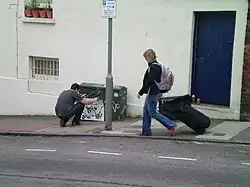 The artist putting a stencil on a utility box in Brighton, 2008
