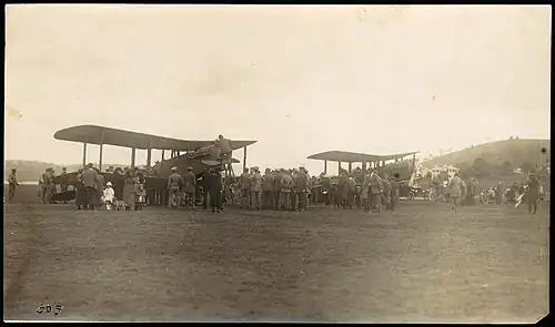 Two biplanes in a field surrounded by a crowd