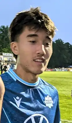 Player in blue uniform walking on the pitch and high fiving a fan