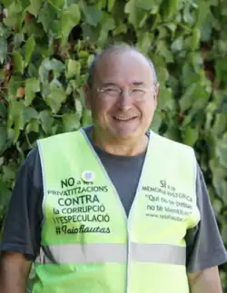 caucasian male with male pattern baldness wearing spectacles and a high-visibility jacket with protest slogans
