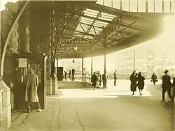 black-and-white photo of people standing outside building with covered entryway