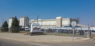 A color photograph of a manufacturing building with a sign that says "Kellogg's" in front