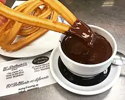 A plate of churros with a cup of chocolate