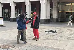 Two reporters, one with a camera, interview Amazon Labor Union President Chris Smalls outside of the NLRB office.