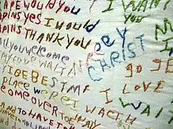 Embroidery art with nonlinear text sewn into it with multiple colors of thread