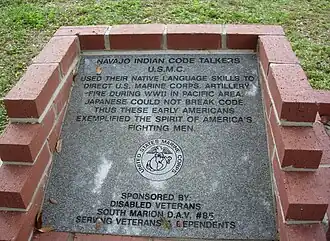 Code talker memorial with etched words: "Navajo Indian Code Talkers USMC. They used their native language skills to direct the US Marine Corps Artillery fire during WWII in the Pacific area. Japanese could not break the code. Thus, these early Americans exemplified the spirit of America's fighting men. Sponsored by: Disabled Veterans South Marion DAV#85 serving veterans and dependents." The memorial also includes the United States Marine Corps emblem.