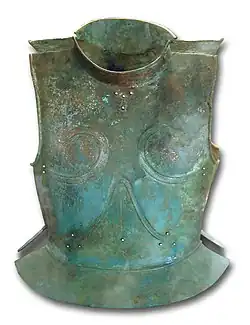Color photograph of bronze upper body armor, a little rusted, superimposed on a white background.