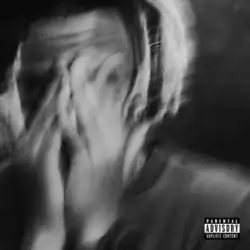 A blurry black and white photo of Cordae covering his face with his hands