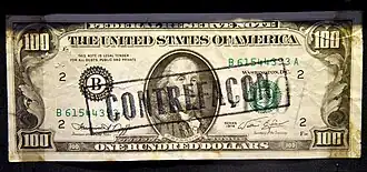 An overprinted Series 1974 counterfeit $100 bill, marked 'Contrefaçon' (counterfeit in French) to indicate its status as a fake banknote