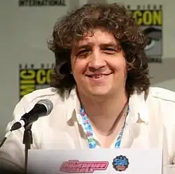 A man (Craig McCracken) with short, curly brown hair at a panel, smiling.