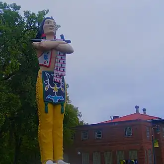 Cartoonishly colorful statue of a stereotypical caricatured Native American standing with arms folded