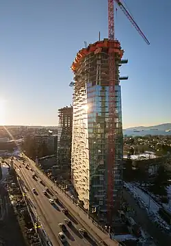 View of a tall tower under construction near a bridge.