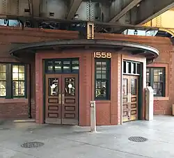 A front-bayed brick building with darker bricks, simpler styling, and dark wood doors