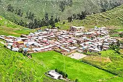 Picture of Hongos, Peru taken from a nearby hillside showing a small, dense town surrounded by green hillsides