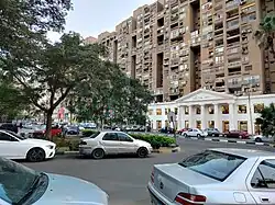 Tree-lined street in Heliopolis with buildings and vehicles