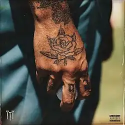 A tattooed hand holding a golf ball.