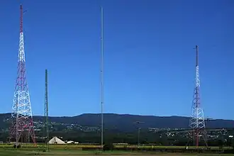 Two metal-truss radio towers against a blue sky.
