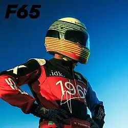 A shot of IDK posing in a multicolored racing suit and helmet under a gradient sky