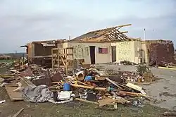 A heavily damaged home with much of its brick exterior and roof destroyed