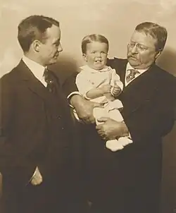 Roosevelt in a white outfit being held by his grandfather